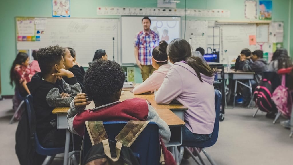 Image: Students in a classroom learning from their teacher. 1 in 7 of these students experience food insecurity, and their primary source of food is the school cafeteria.
