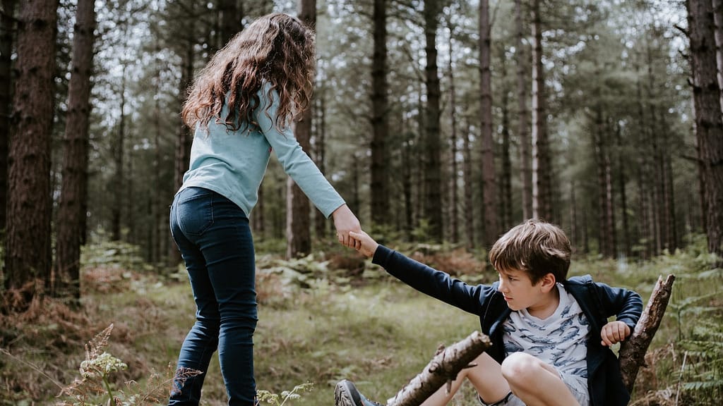 Image: A young girl helping a young boy up off the ground in the woods. Representative of the public's gravitation towards movies like Casablanca, where people are selflessly helping others.