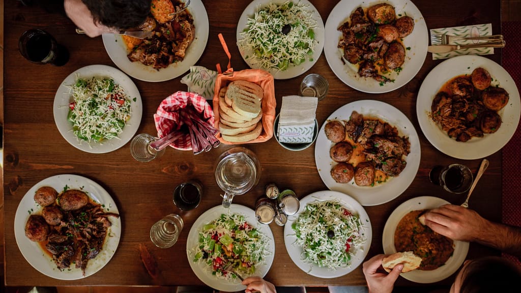 Image: A family dinner, with ten plates full of diverse kinds of food