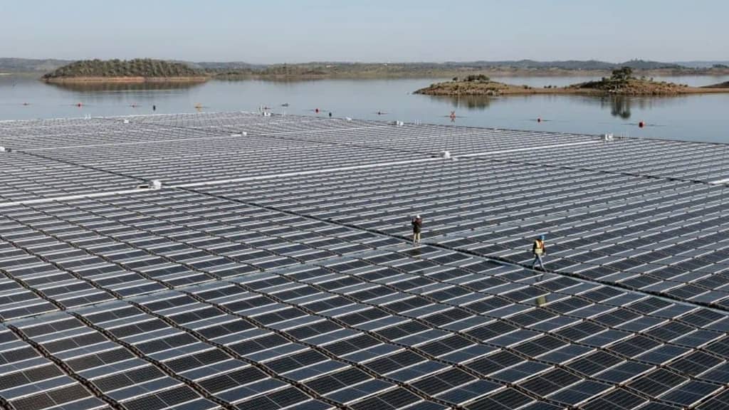 Image: A floating solar farm with two workers walking on top of it.
