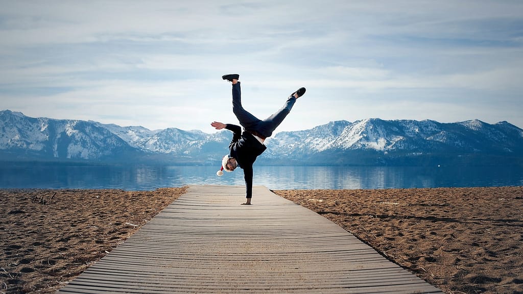 Image: A man mid-cartwheel on a boardwalk in front of a lake, no longer feeling overwhelmed.