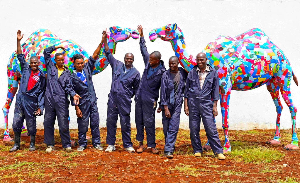 Image: Ocean sole artisans standing with two camels made of recycled flip flops