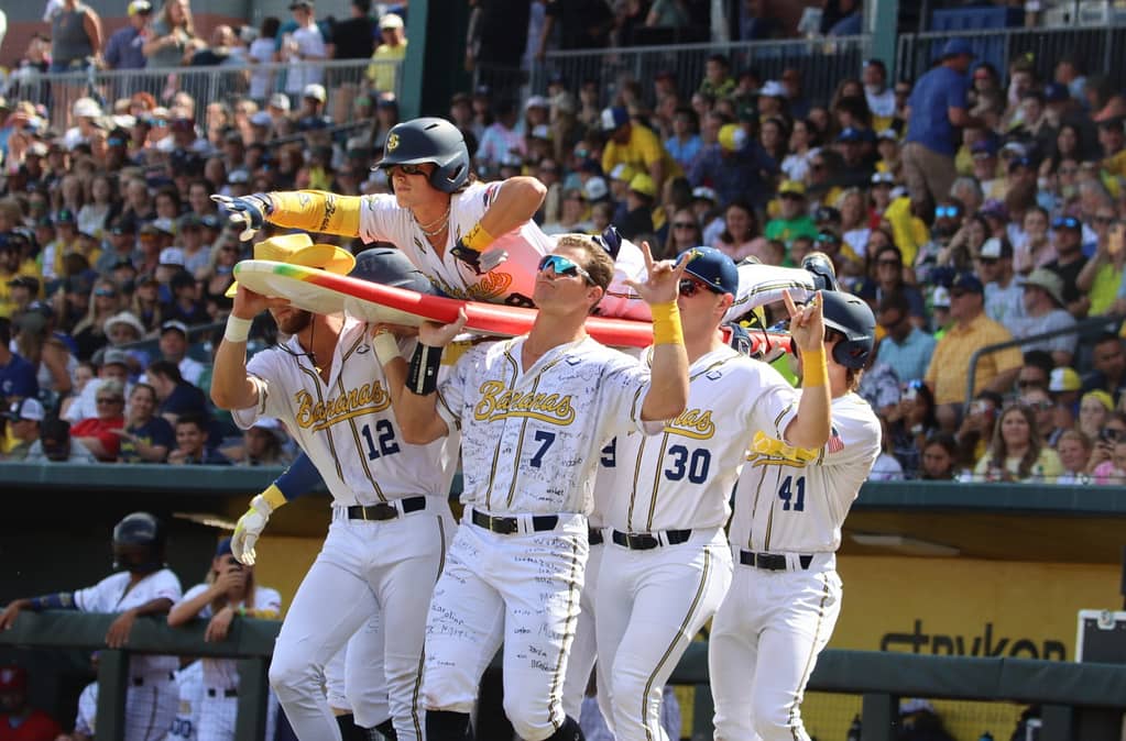 Image: The Savannah Bananas players carry another player onto the field on a surfboard