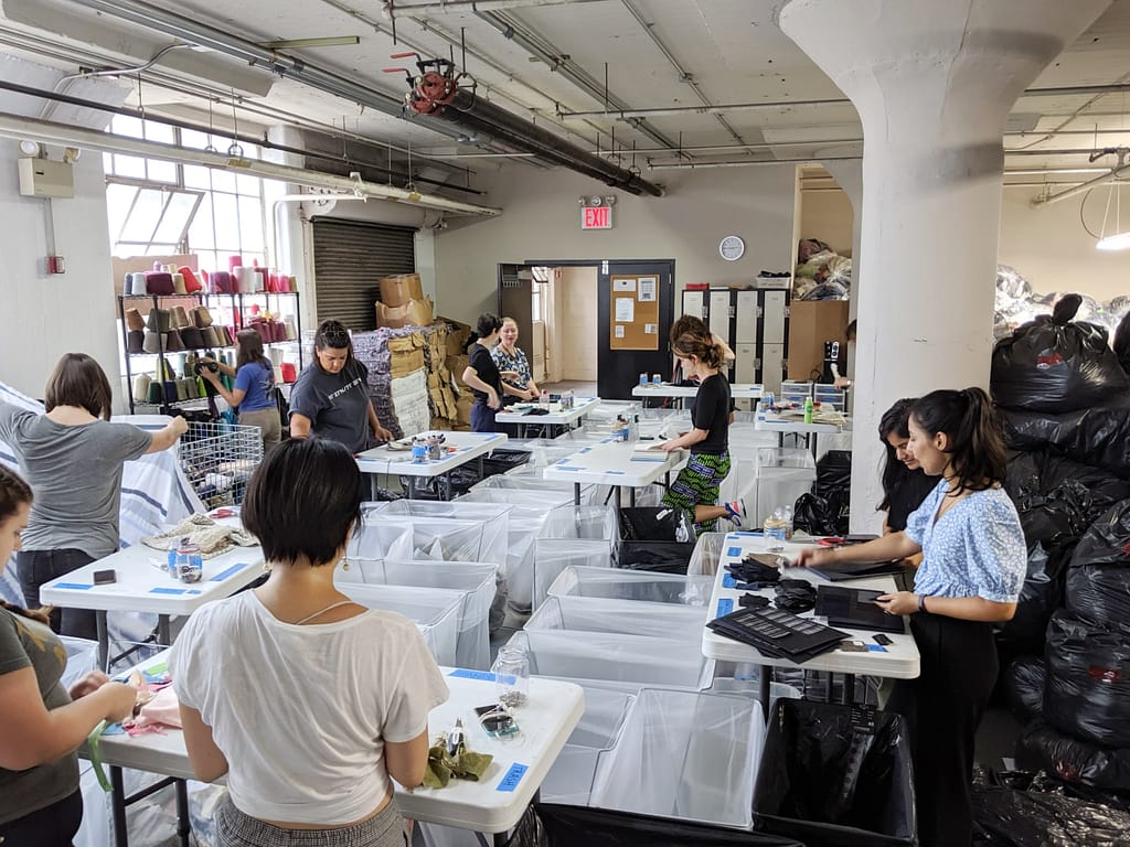 Image: FABSCRAP volunteers sorting and mending fabrics at the FABSCRAP warehouse. 