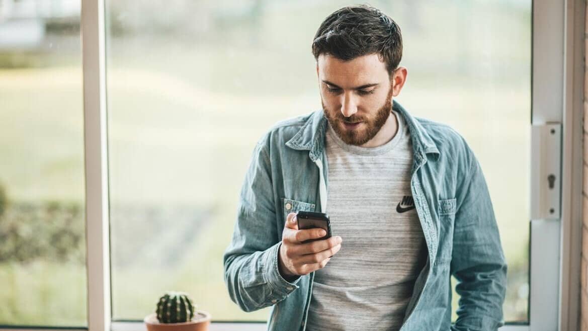 Image: A man leaning against a counter, looking down at his phone. Telemarketer and me.