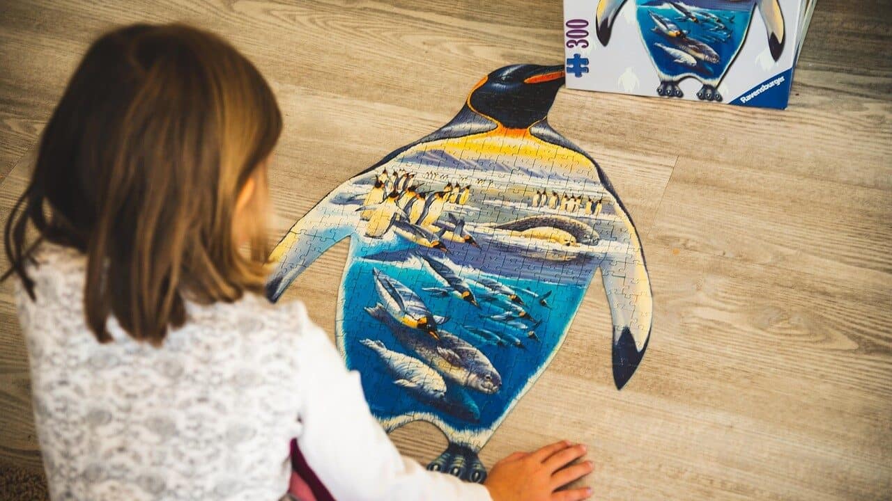 Image: Young child putting together a jigsaw puzzle shaped like a penguin
