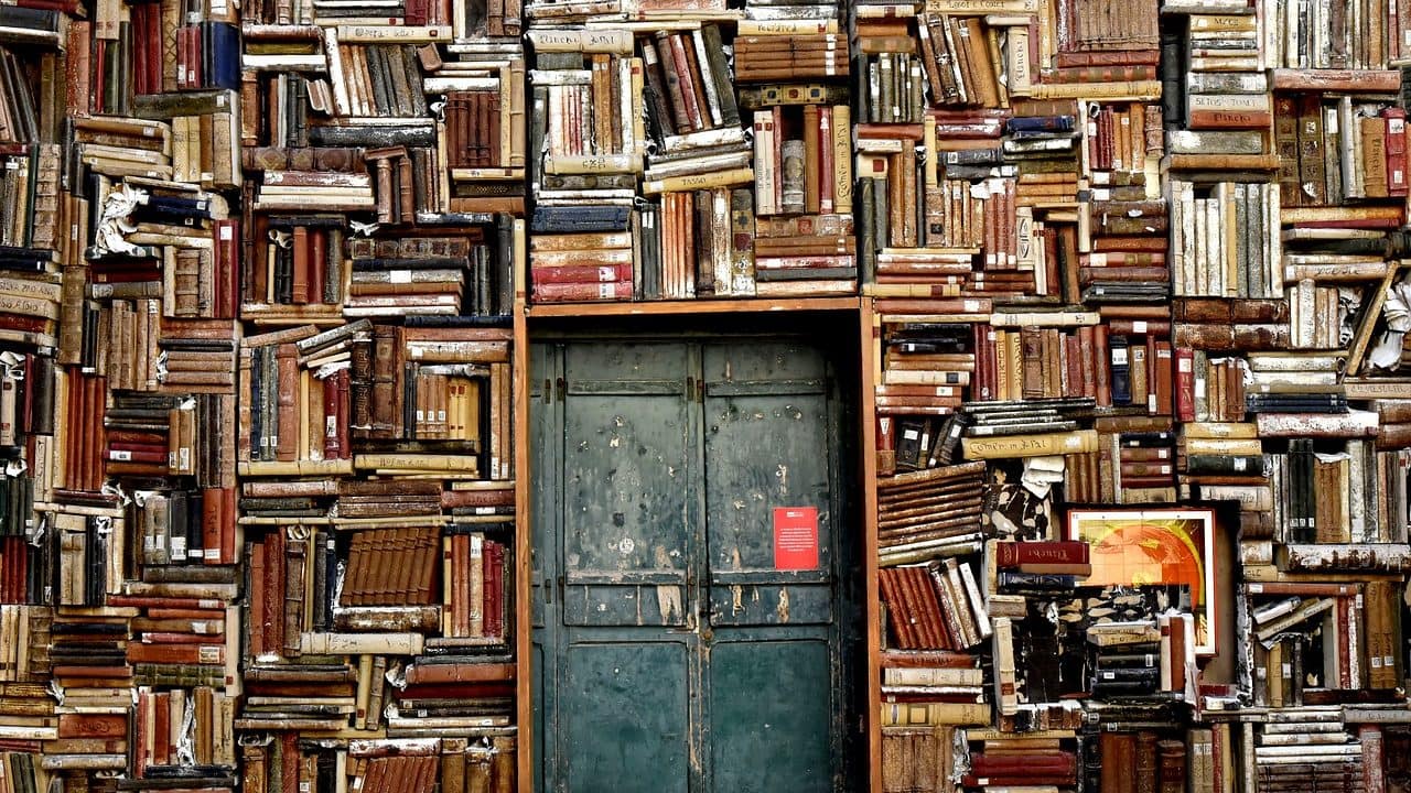 Image: Books stacked along a wall, lining a doorway