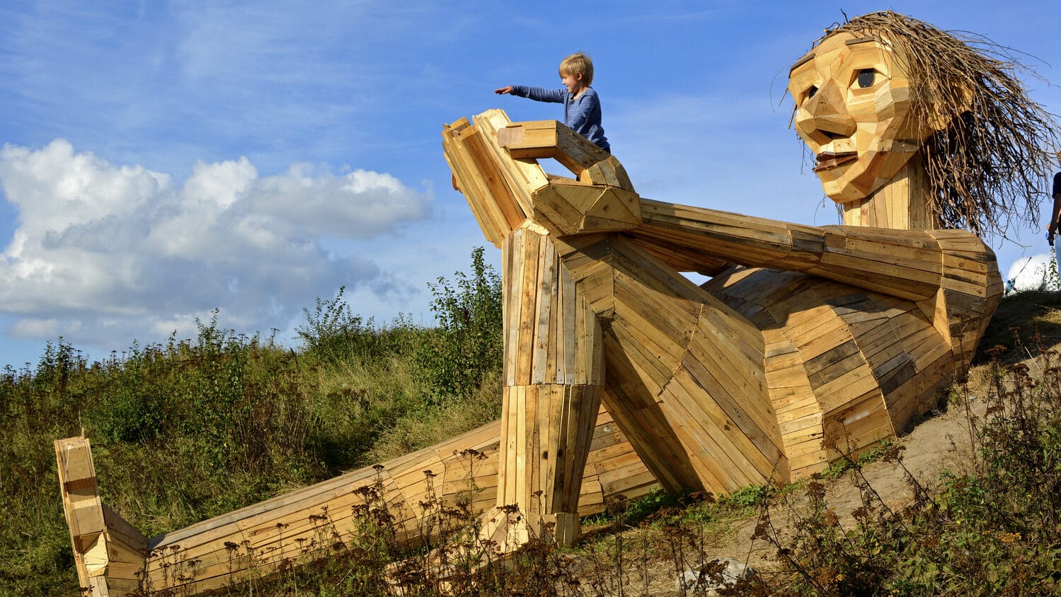 Image: A huge sculpture of a troll, 50 feet long, made of scrap wood.