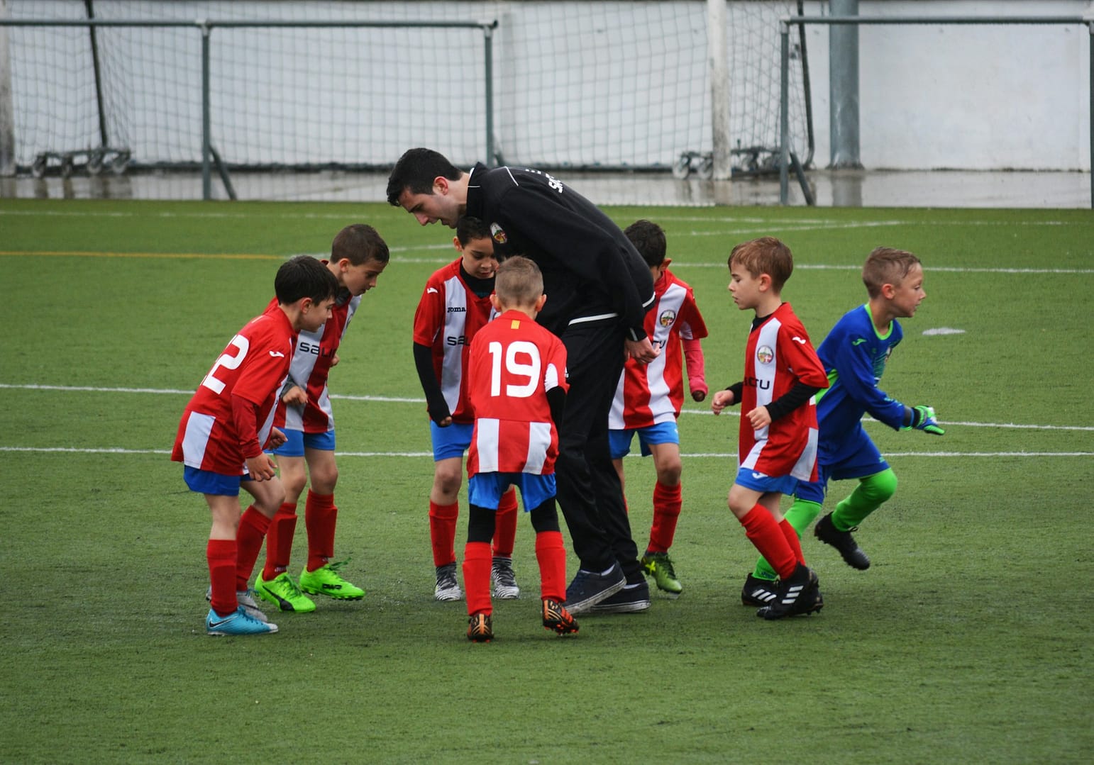Image: soccer coach with youth players in a huddle