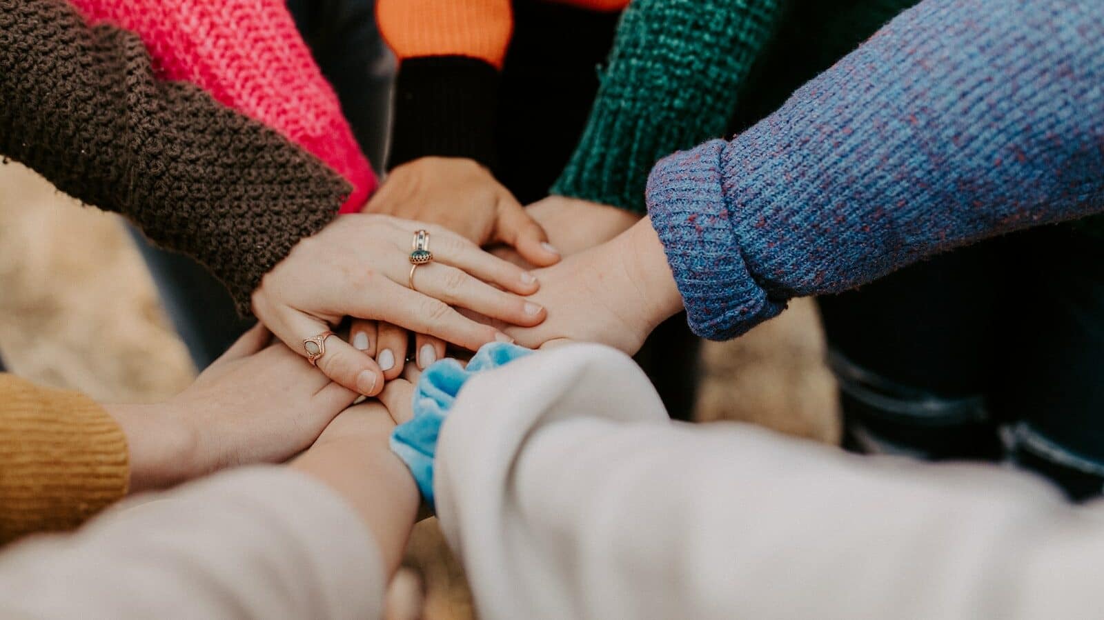 person in red sweater holding babys hand