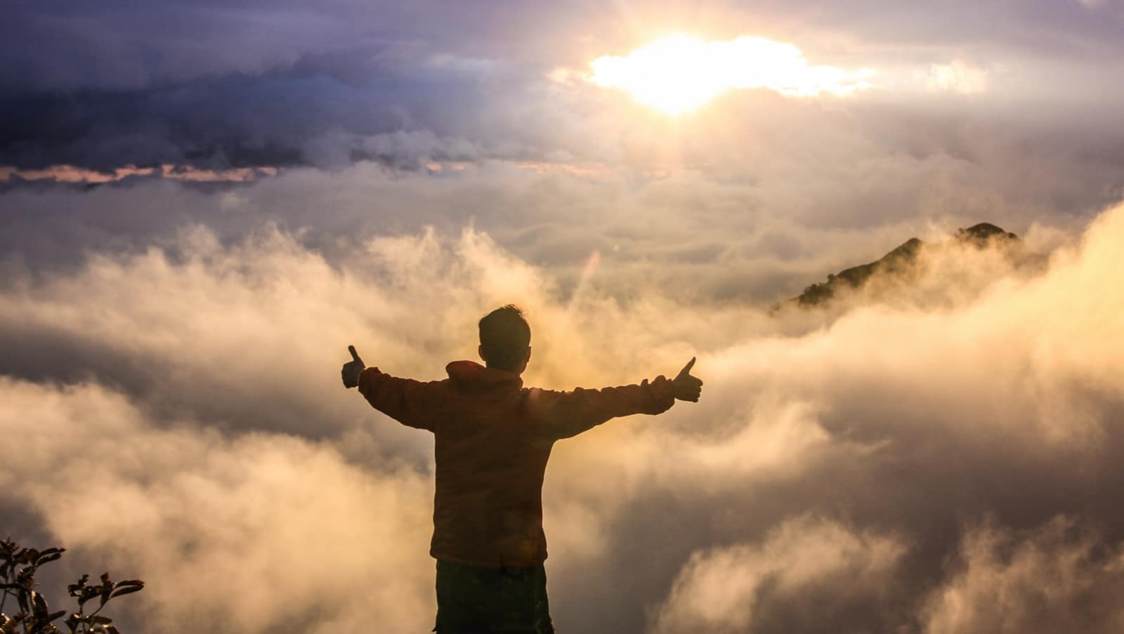 Image: Man with arms spread and thumbs up in sunrise