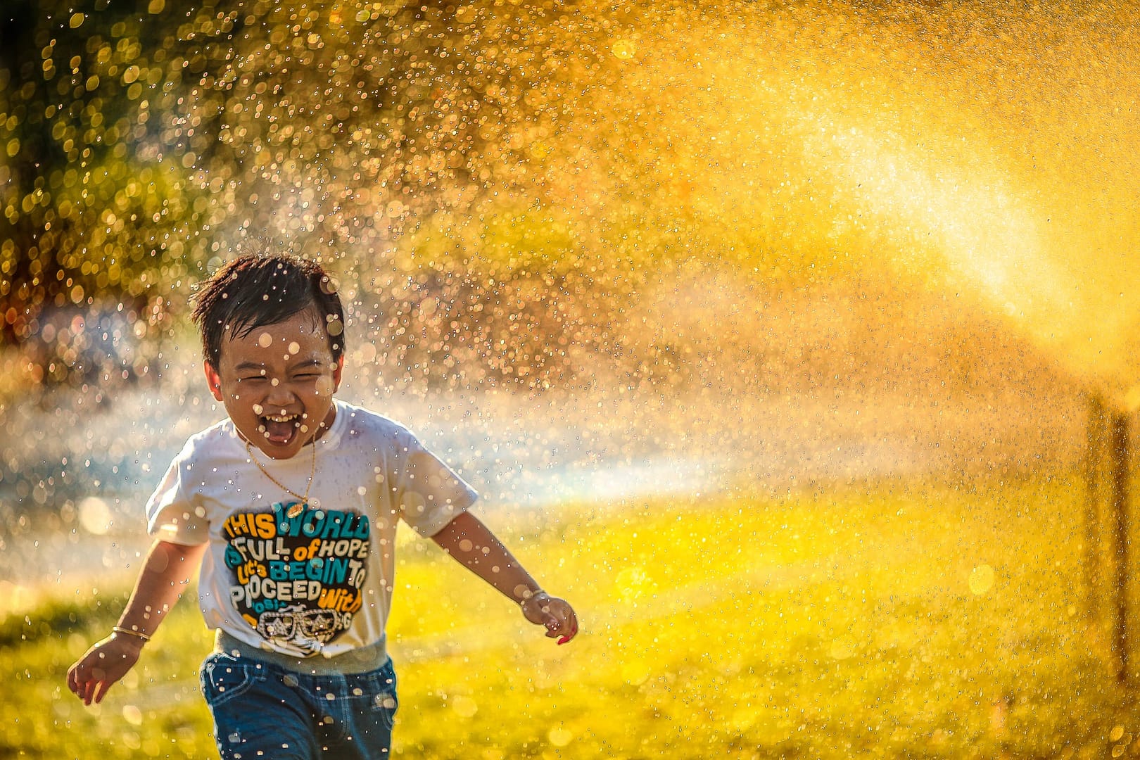 Image: happy child running through a sprinkler in the sun