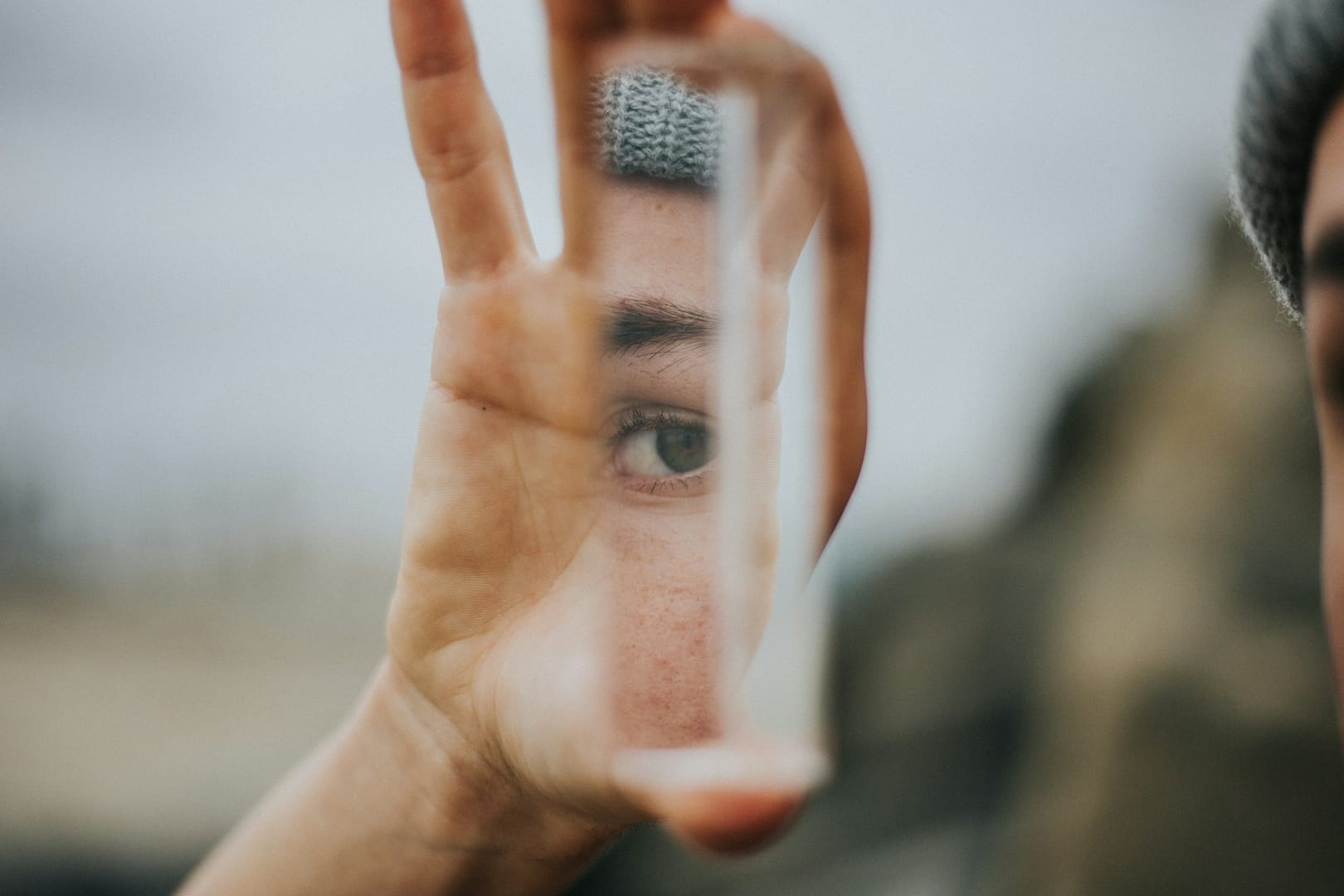 Image: A person holds a prism with just their eye visable