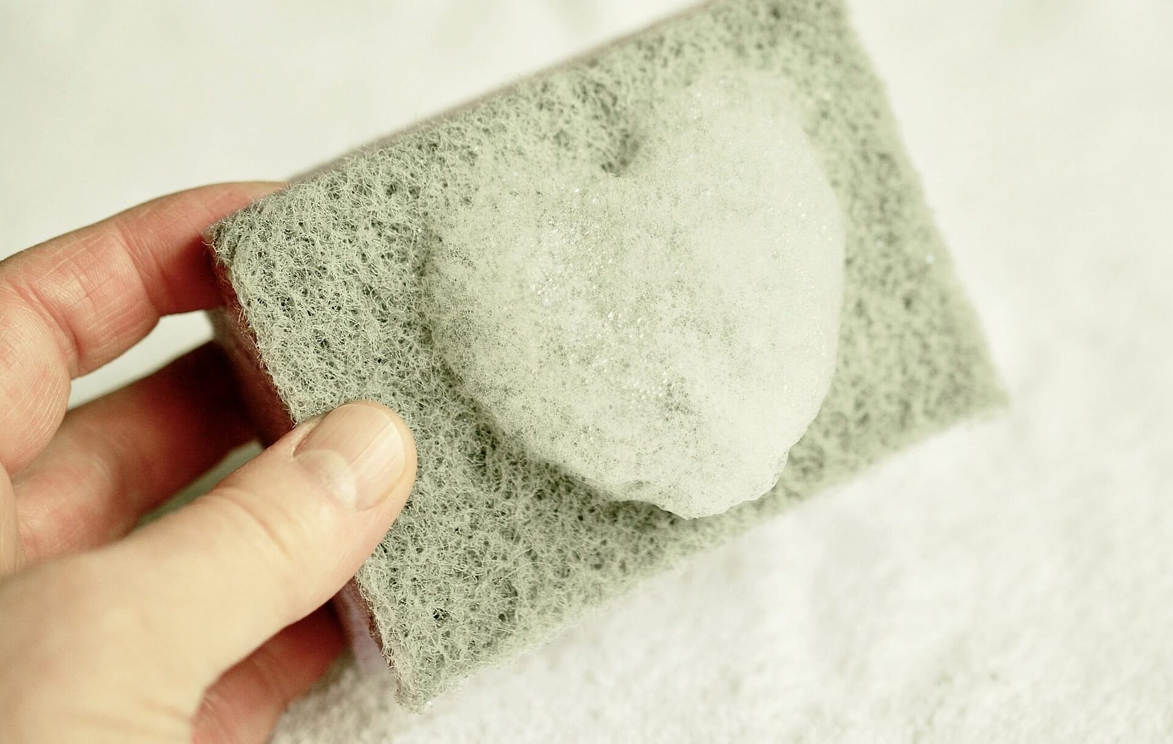 Imge: Hot Mess Express Hand holding a sponge with heart shapes suds