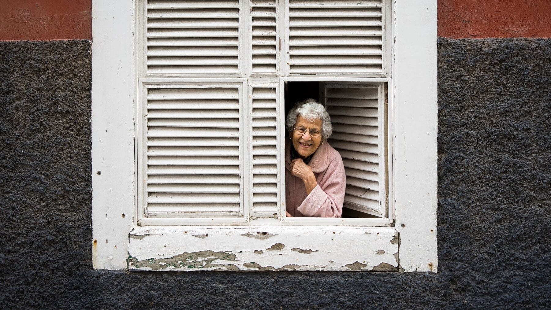 Image: Elderly woman peering out her shuttered windows smiling!