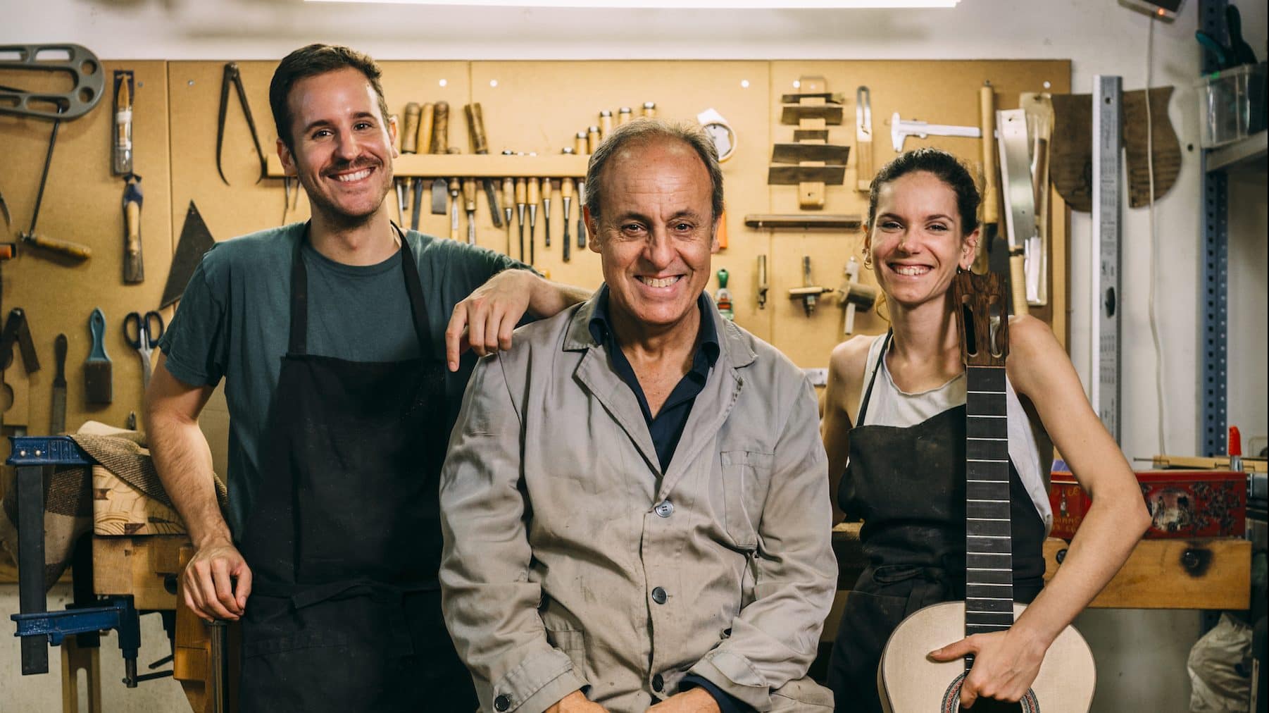 Image: Luthiers team having fun while posing in their family business. Looking at camera