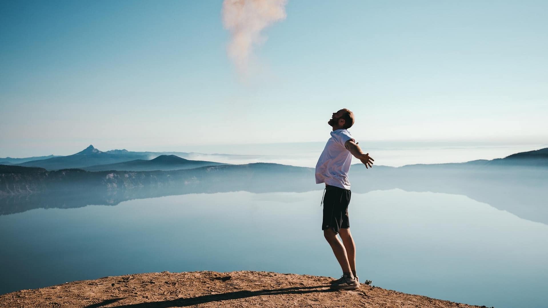 Image: A man smiling in front of a beautiful view. Intrinsic Happiness.