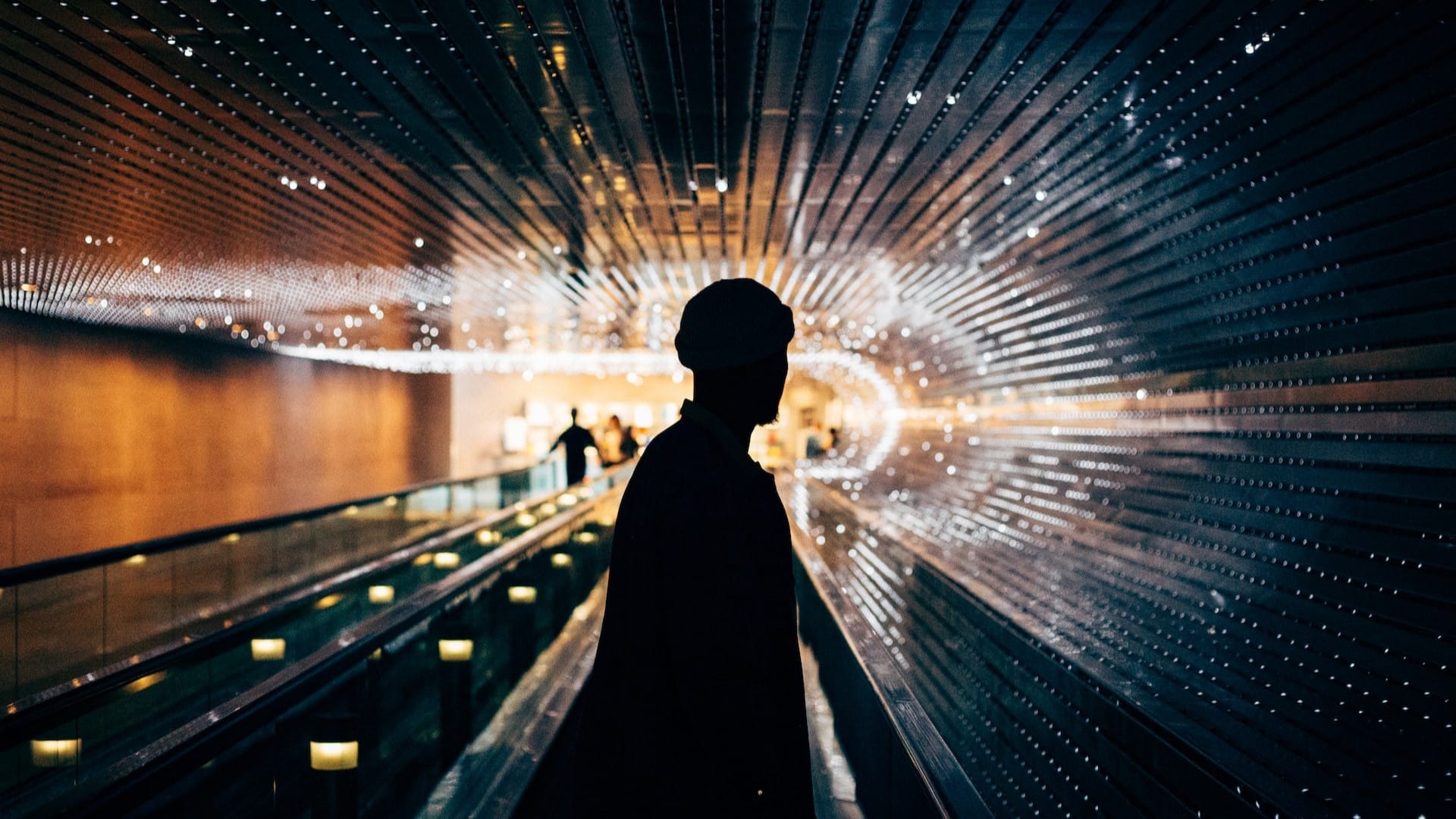 Image: the silhouette of a man with bright lights shining behind him.
