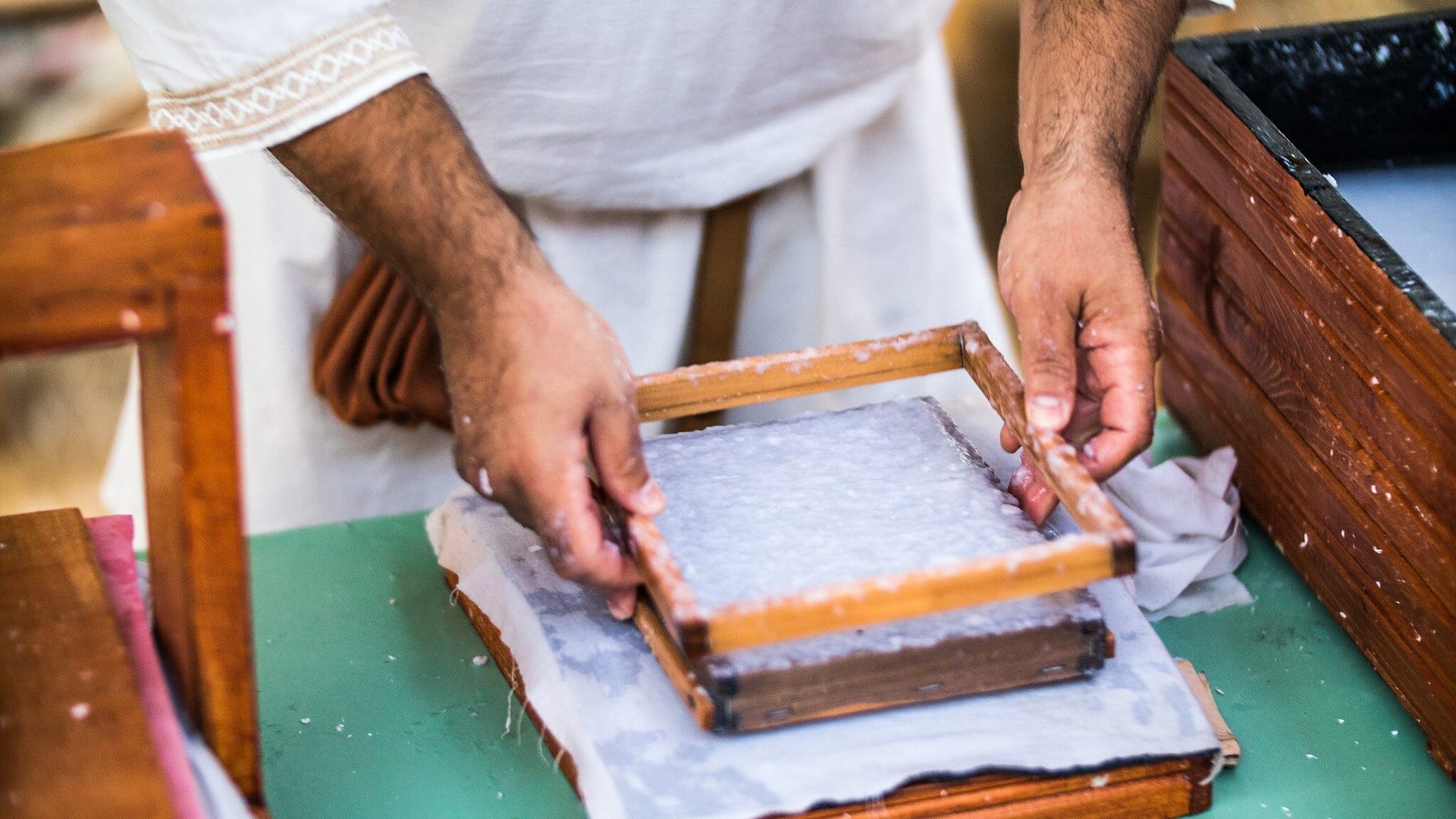 Image: Person pulling the deckel off of a freshly made piece of paper