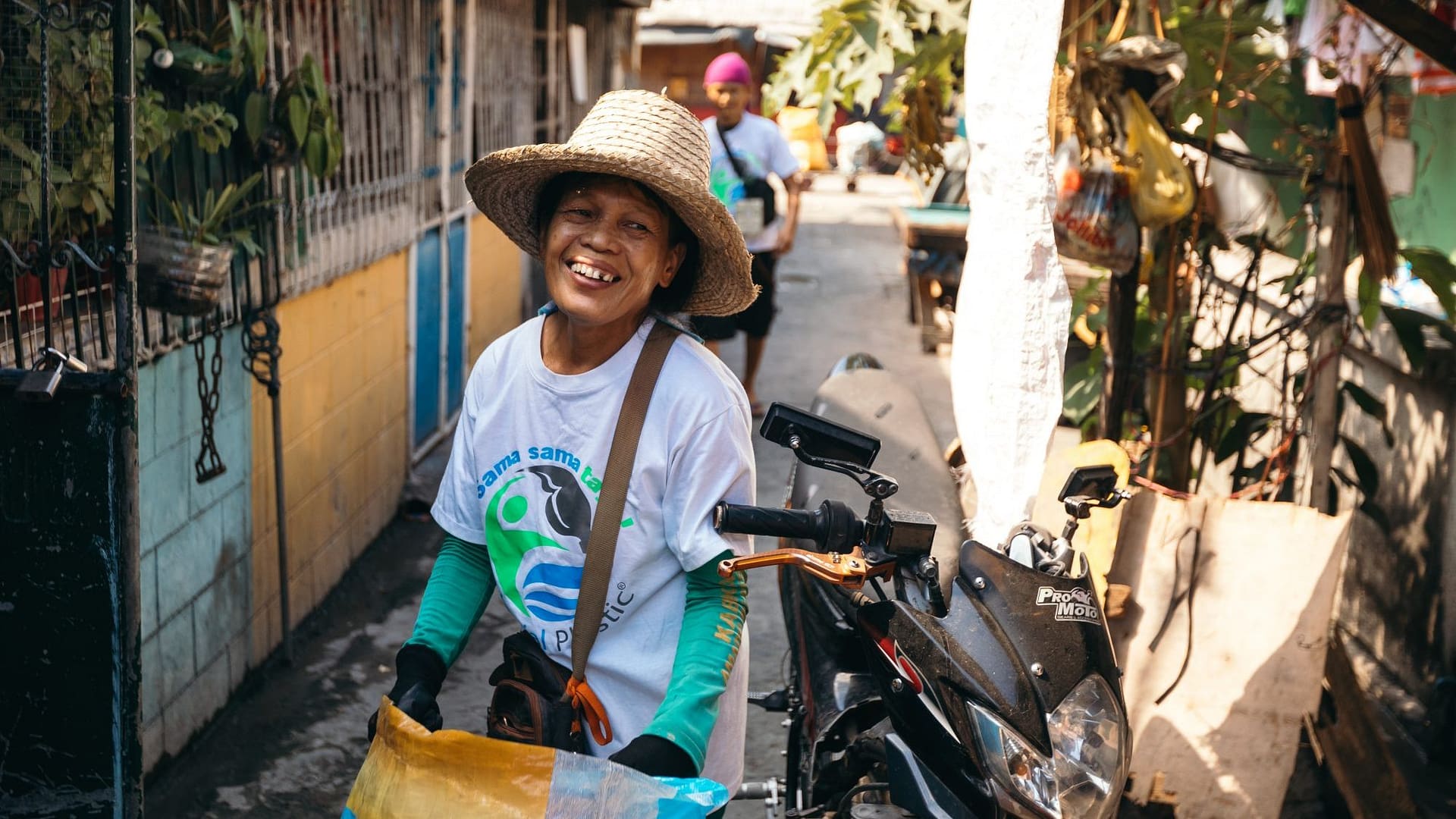 Image: Woman carrying bags of plastic in the Philippines and smiling