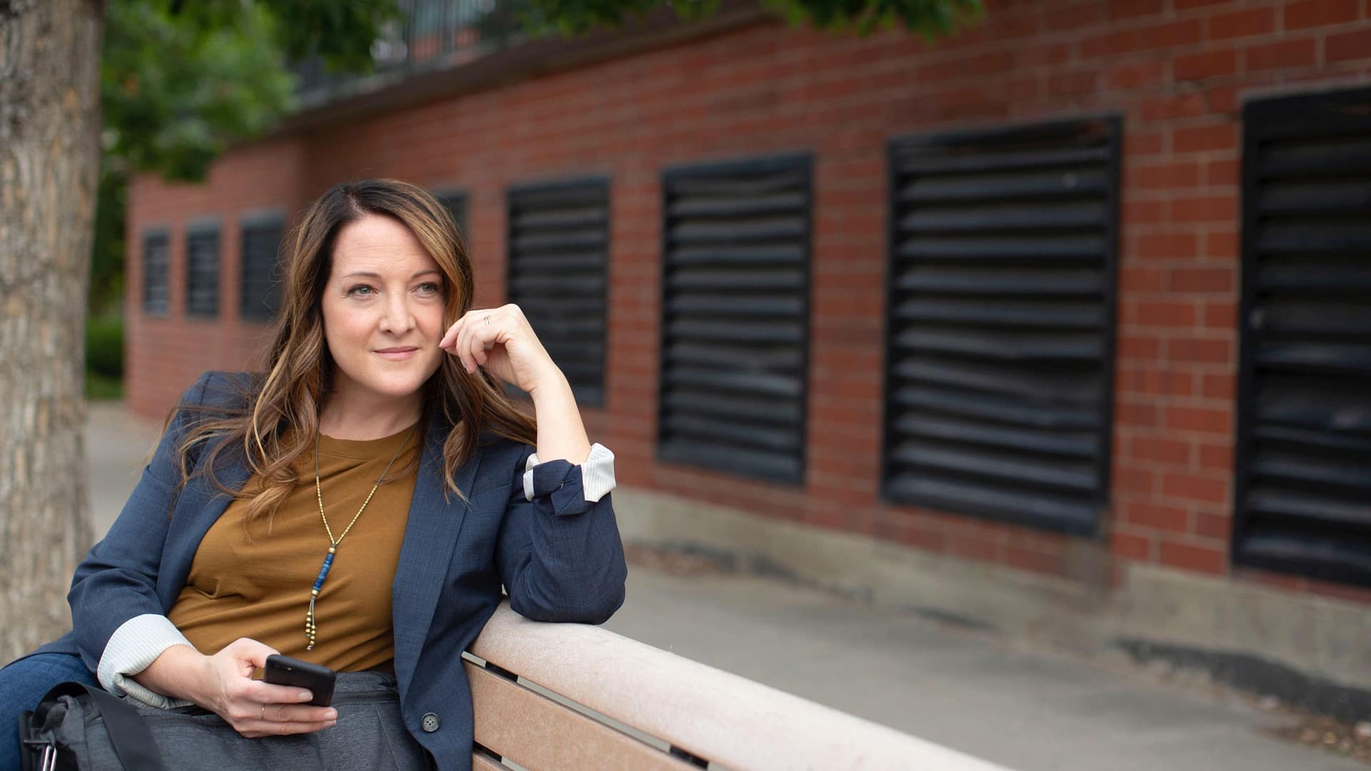 Image: A woman sitting on a bench looking contemplative.