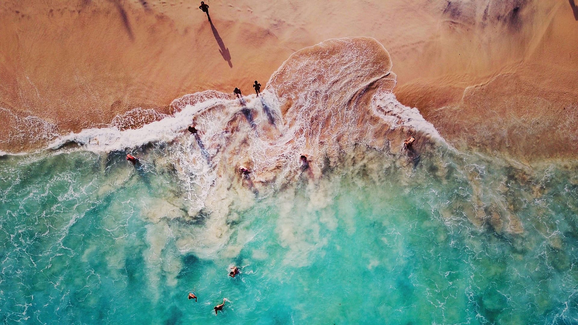 Image: The tide rolling in on a beach from above.