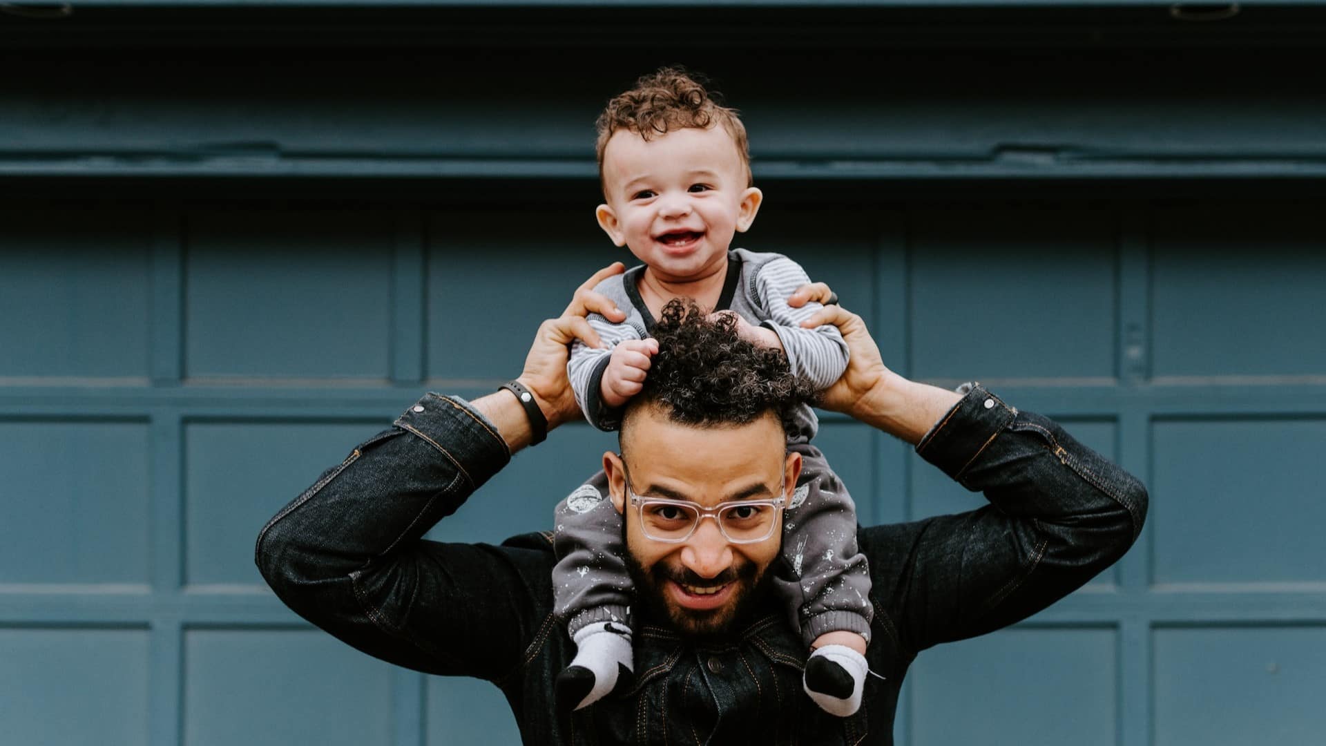 Image: A young boy sitting on his father's shoulders