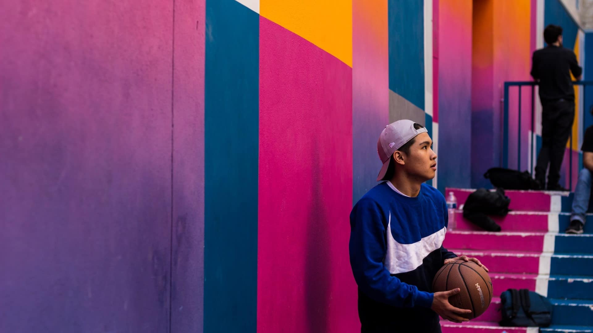 Image: A man standing in a colorful basketball court holding a basketball.