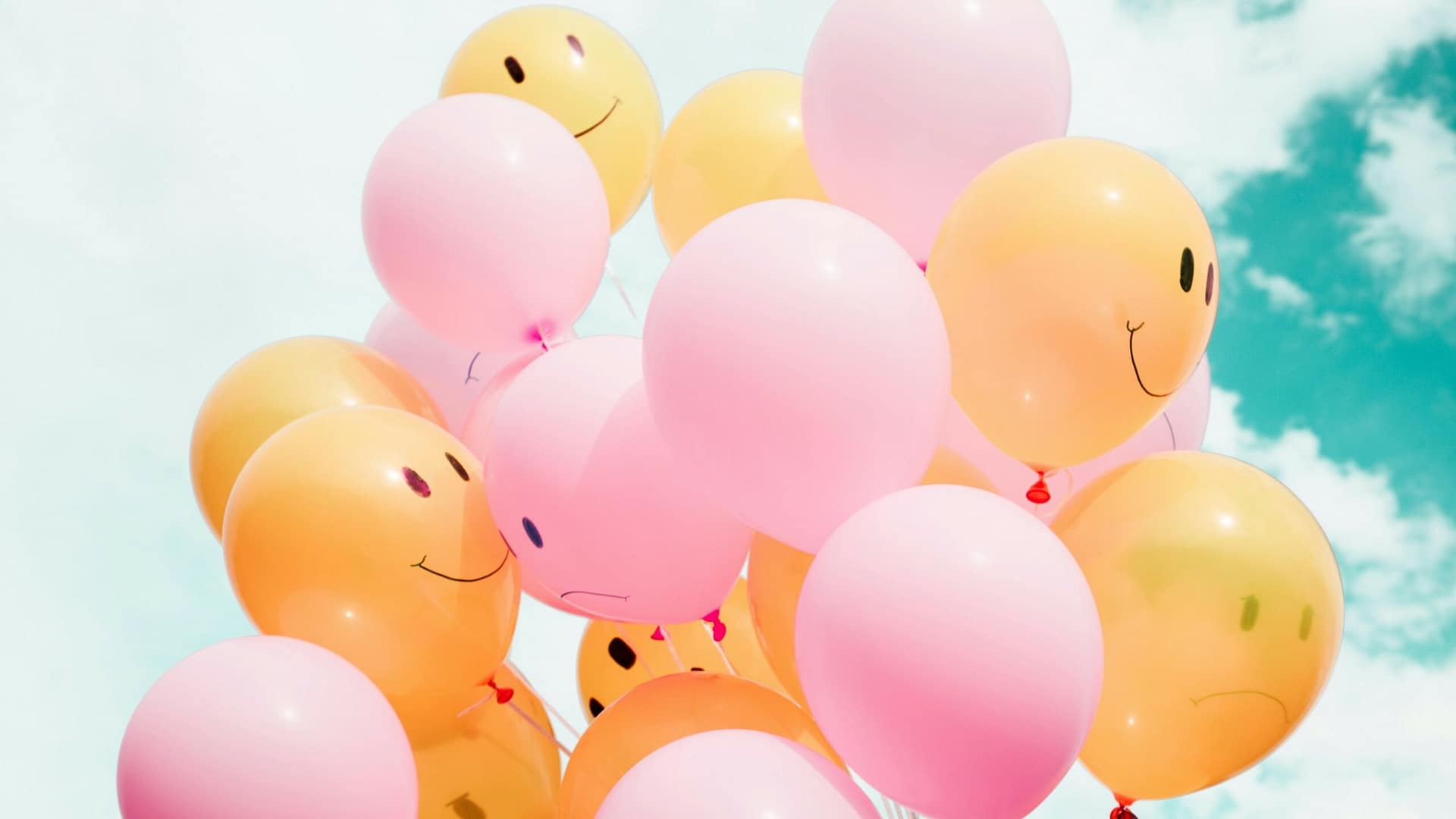 a cluster of balloons with positive smiling faces on them