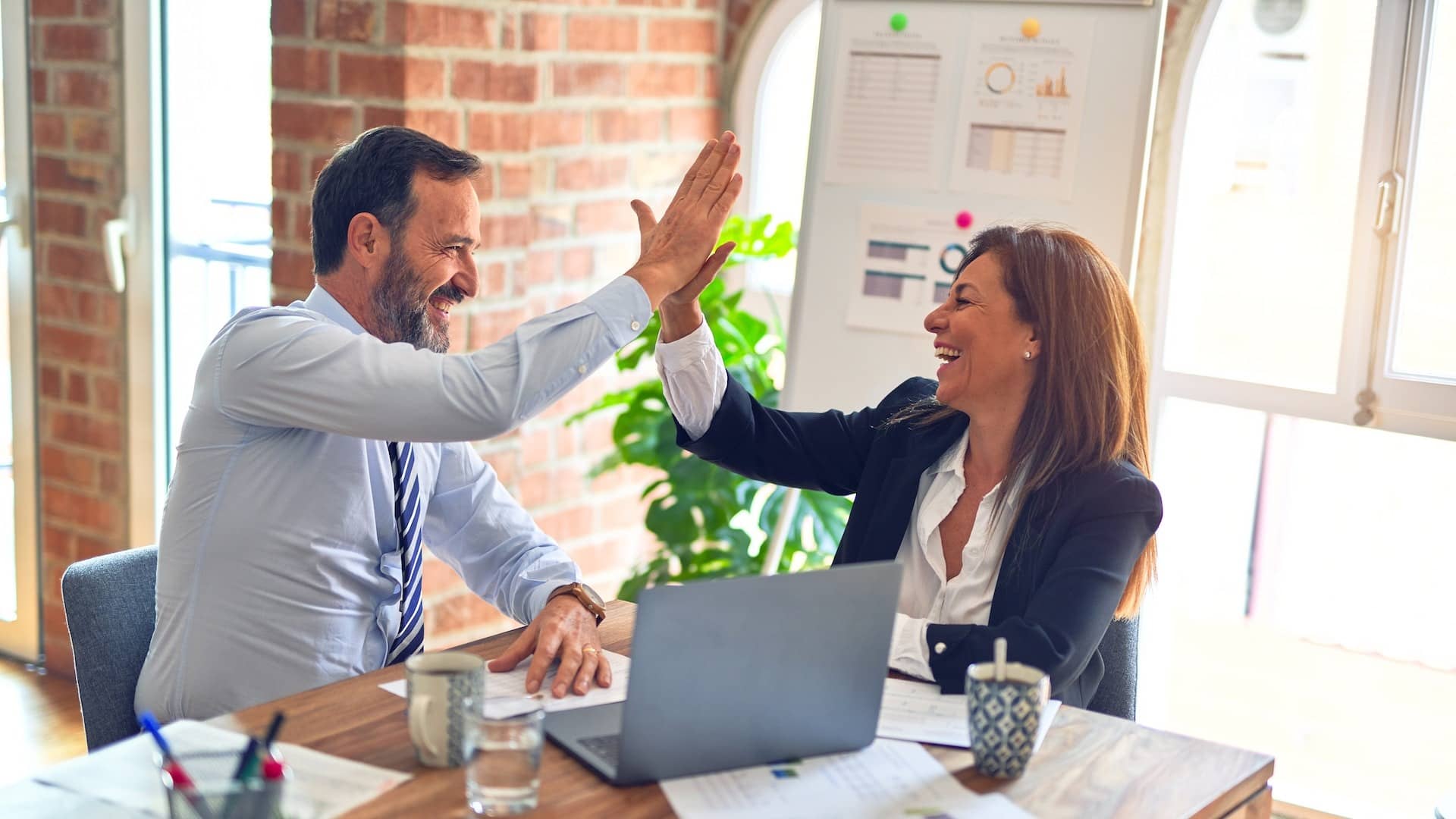 Image: A man and a woman in a professional office, high fiving