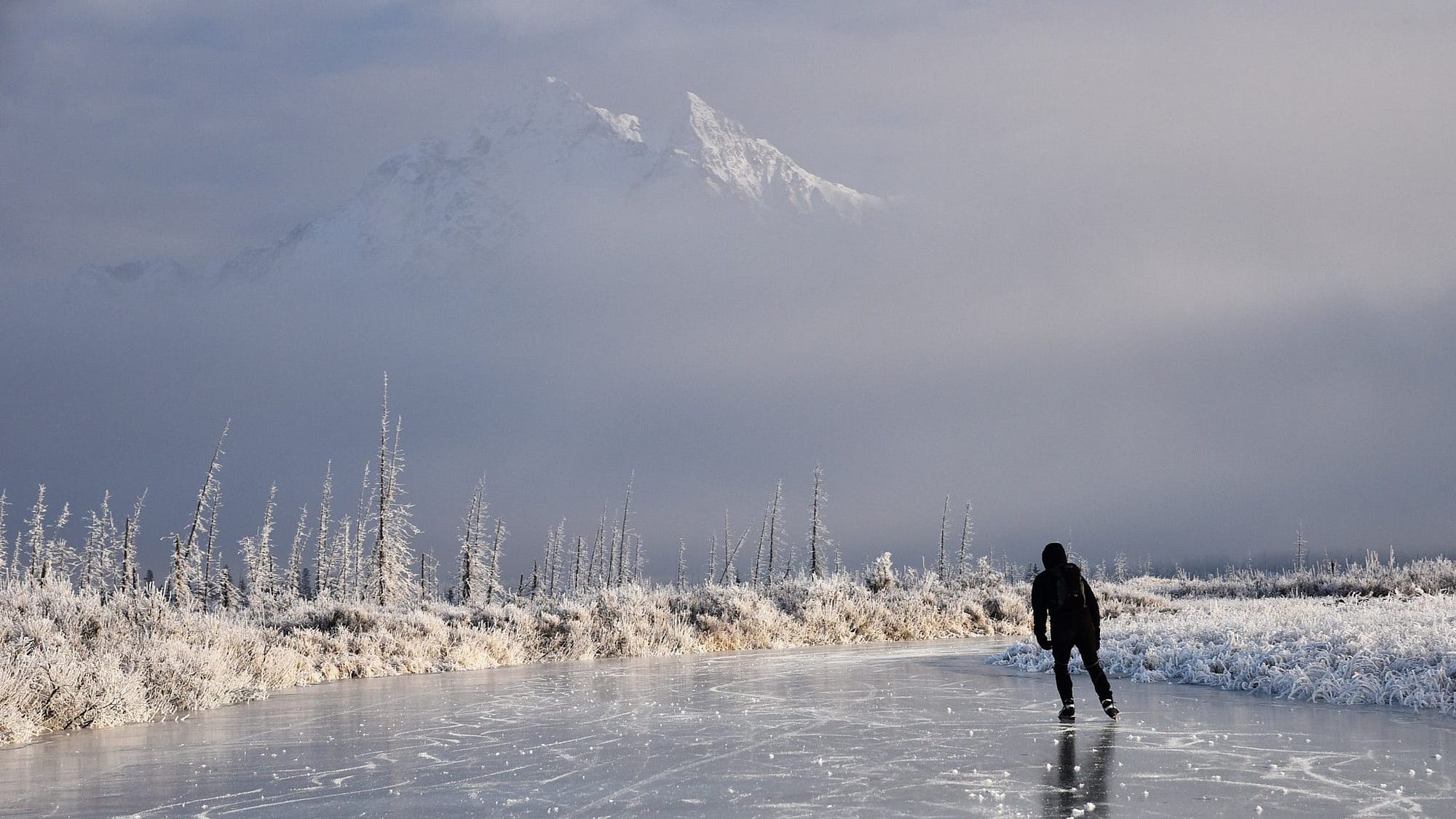 Image: lone ice skater skating in the wilderness with a mountain in the background