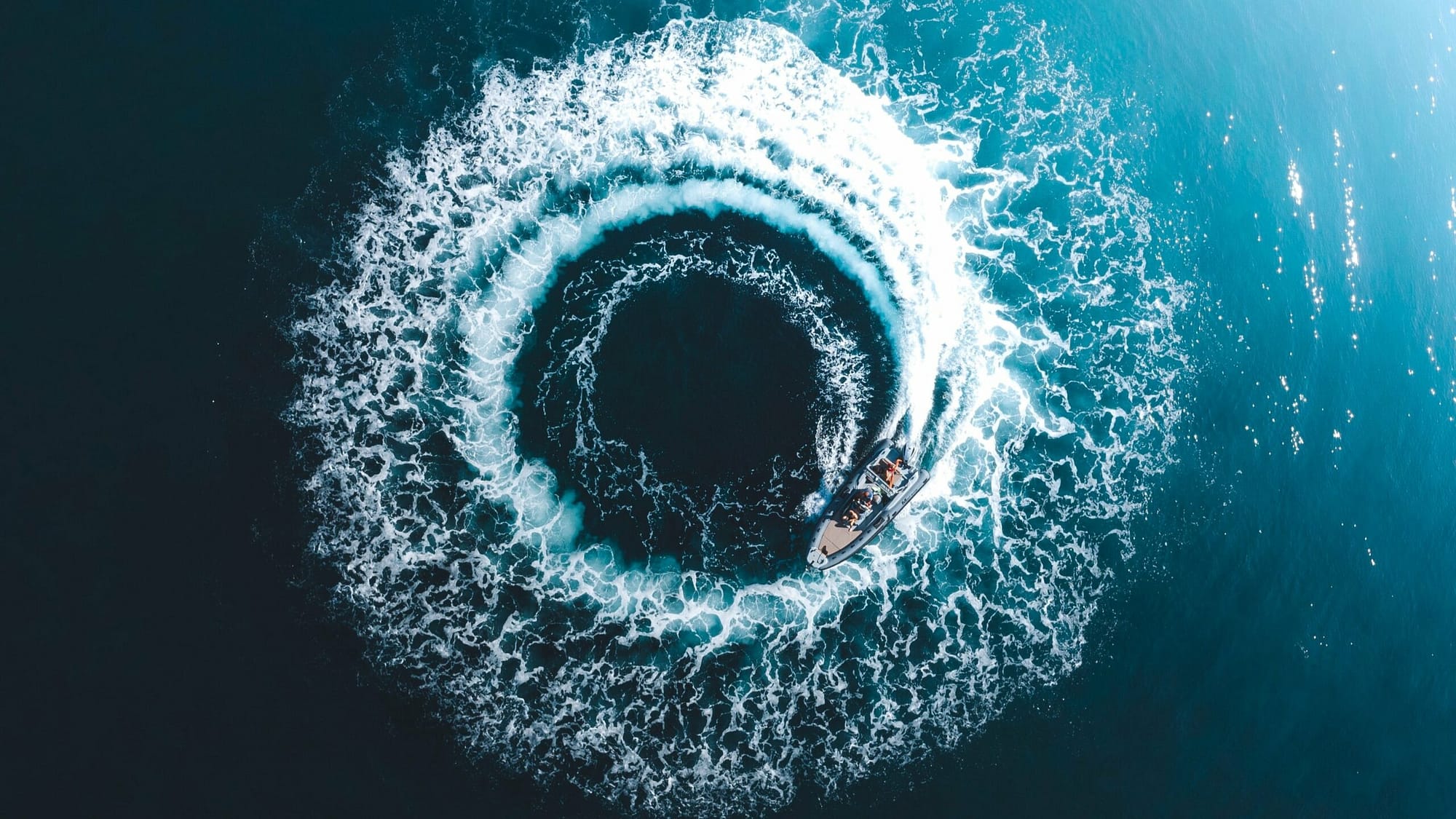 Image: A boat creating a circular wave behind it in the ocean, representing how preventing things is much easier than dealing with their fallout.
