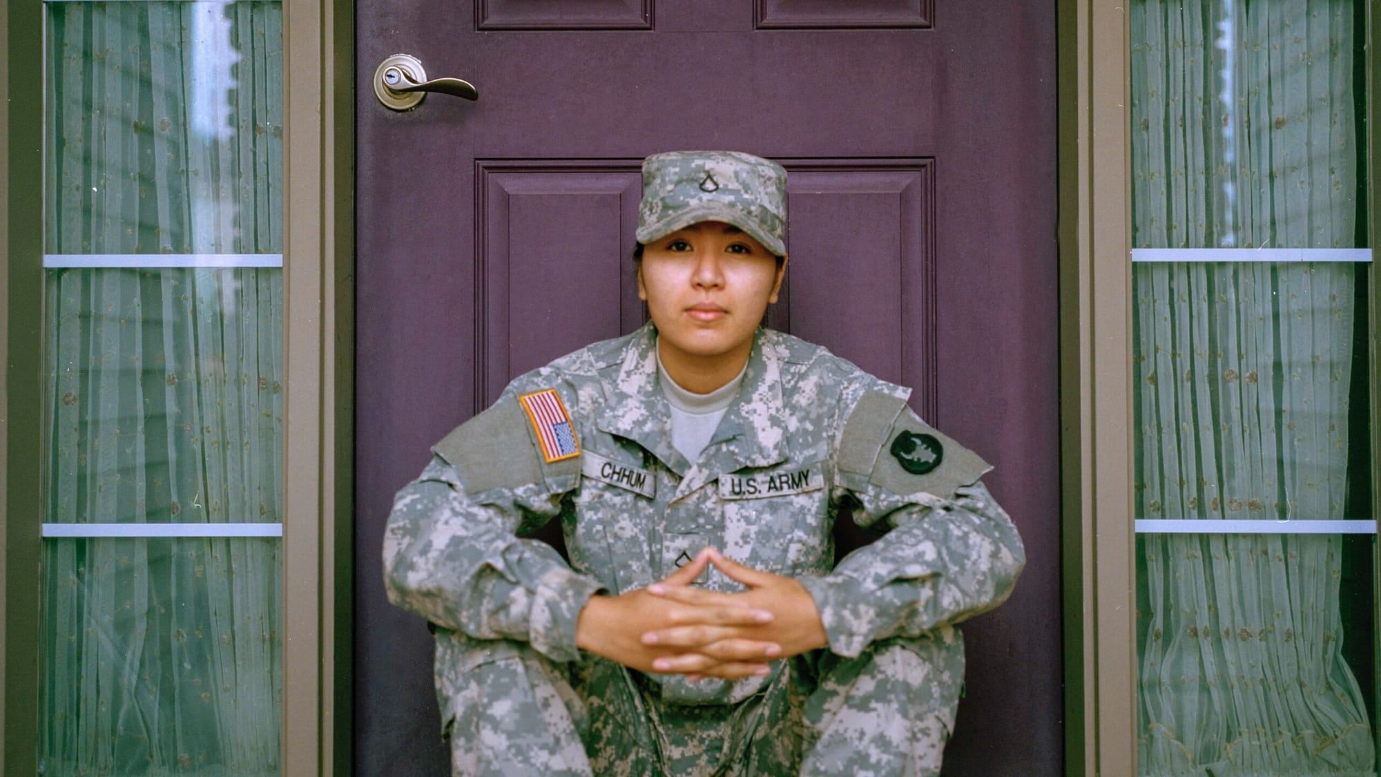Image: A veteran of the US Army sitting in front of a purple door.