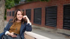 Image: A woman sitting on a bench looking contemplative.
