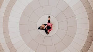 Image: a woman dressed business casual walking across a square, image taken from above