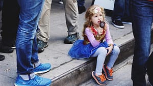 Image: Young kid in a superhero costume eating ice cream on the curb!