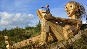 Image: A huge sculpture of a troll, 50 feet long, made of scrap wood.