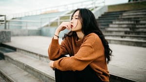 woman wearing brown sweater holding lips
