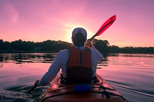 Image: Person kayaking with their back to the camera, heading off into the sunset