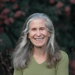 Image: portrait style photograph of Zoe Weil standing in front of a background of nature