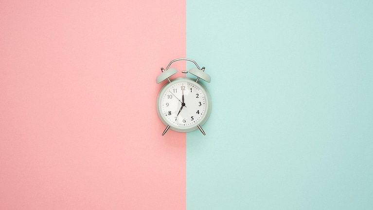 Image: Alarm clock on a background with two different colors splitting the image down the middle