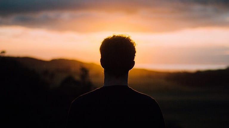 Image: Silhouette of a short haired person staring at the sunset