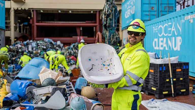 Image: A worker with the ocean cleanup project holding some of the trash that system 002 has pulled from the ocean