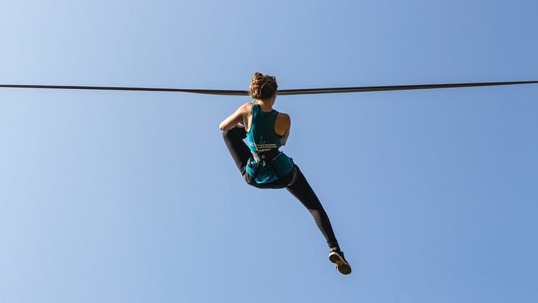 Image: A woman hanging from a slackline while slacklining