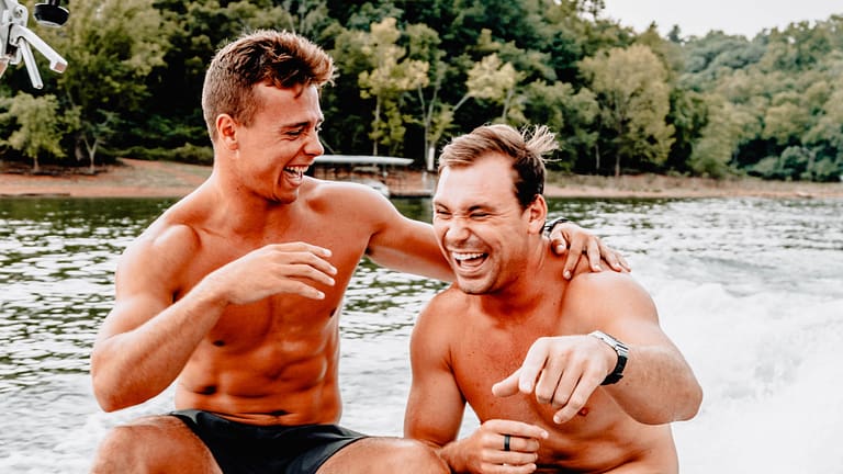 Image: Two men sitting on a boat laughing hysterically, having fun