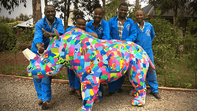 Image: Five Ocean Sole artisans standing with a large rhino, made entirely of recycled flip flops.