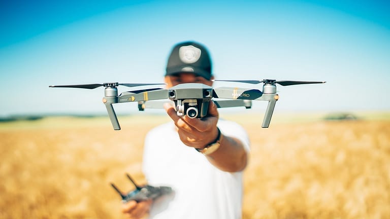 Image: A man holding a drone up to the camera.