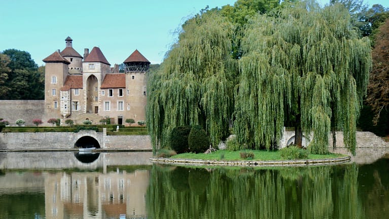 Image: castle on the water with willow trees on the bank