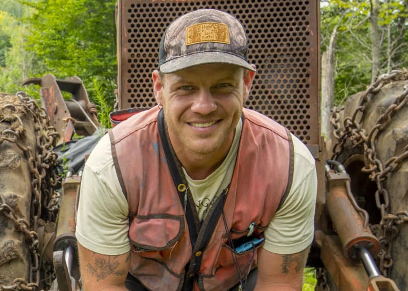 Forester, Author, and Creator poses outdoors wearing a high-vis vest.