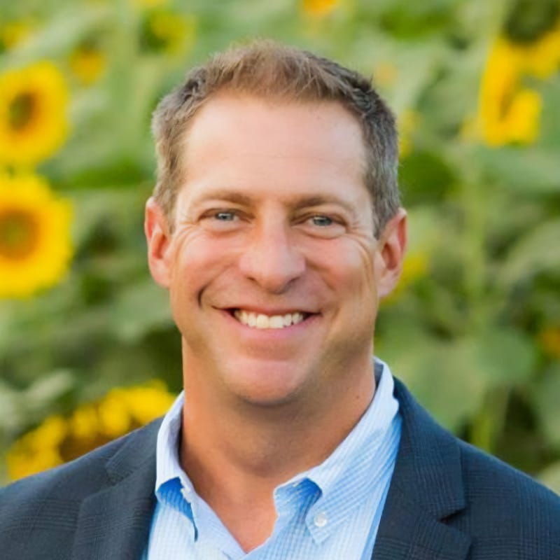 Darrin Tulley smiles against a a field of sunflowers